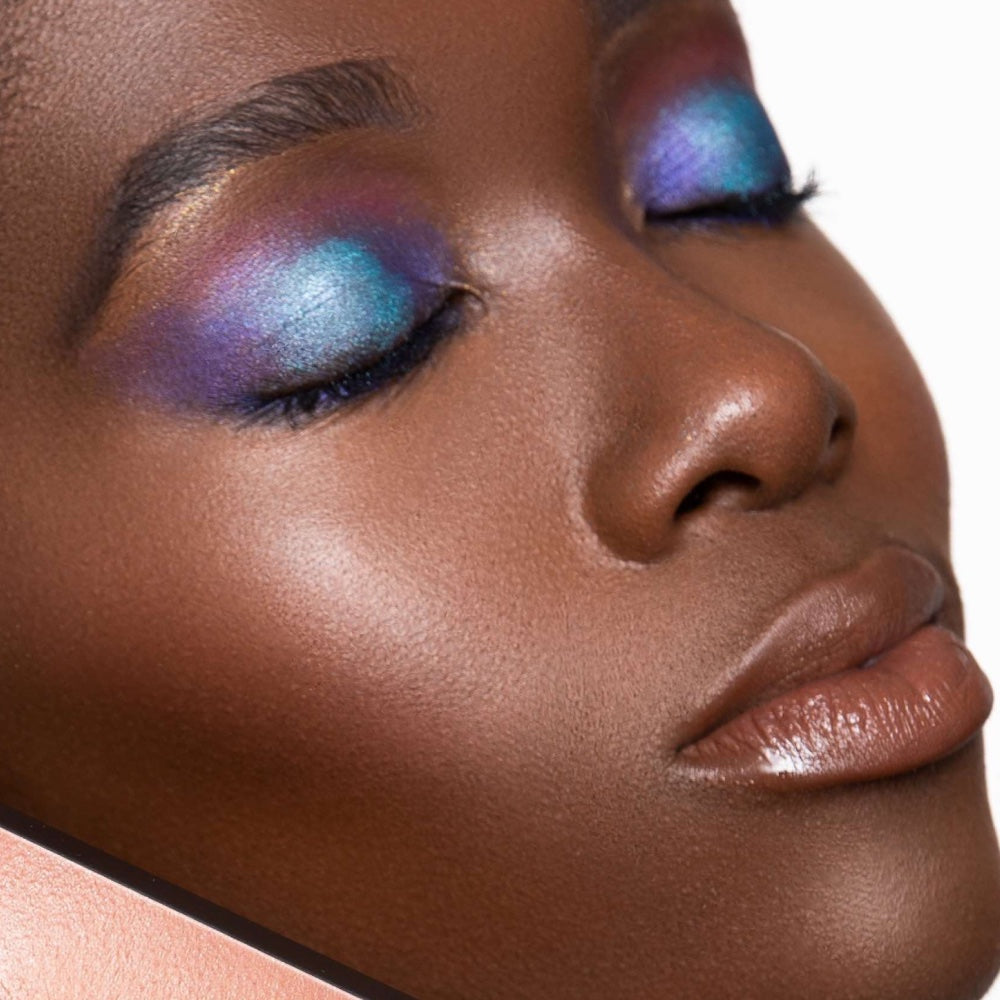 Close up image of a woman with closed eyes with shades of blue and green eyeshadow.